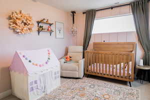 Bedroom with a crib, visible vents, and light colored carpet