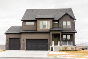 View of front of property featuring a shingled roof, concrete driveway, brick siding, and fence