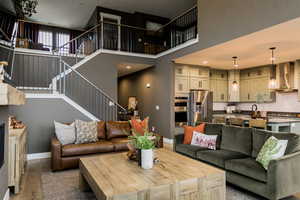 Living area with stairs, a high ceiling, wood finished floors, and baseboards