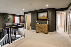 Corridor with light carpet, baseboards, visible vents, and recessed lighting