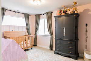 Bedroom with a nursery area, light colored carpet, and baseboards