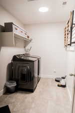 Washroom featuring laundry area, washing machine and dryer, visible vents, and baseboards