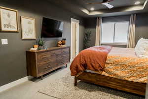 Bedroom with recessed lighting, baseboards, a raised ceiling, and light colored carpet