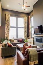 Living area featuring a glass covered fireplace, plenty of natural light, light wood-style flooring, and ceiling fan