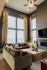 Living room featuring ceiling fan, wood finished floors, and a glass covered fireplace