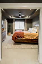 Bedroom with ceiling fan, carpet floors, a raised ceiling, and baseboards