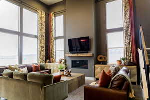 Living room featuring a high ceiling, a wealth of natural light, and a glass covered fireplace