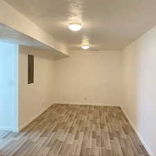 Finished basement featuring light wood-type flooring, electric panel, and baseboards