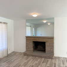 Unfurnished living room featuring a fireplace, wood finished floors, visible vents, and baseboards