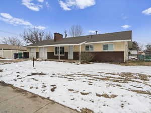 Ranch-style house featuring brick siding, fence, a chimney, and an attached garage