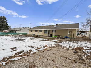 Snow covered rear of property with a patio area and fence