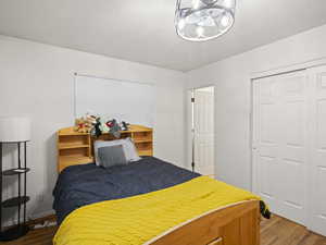 Bedroom featuring dark wood-style flooring, a closet, and a notable chandelier