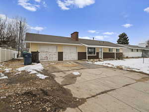 Ranch-style house featuring brick siding, a chimney, fence, a garage, and driveway