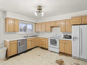 Kitchen featuring a sink, light floors, white appliances, and light countertops