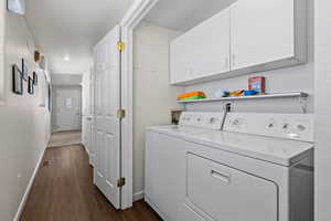 Washroom with dark wood-style floors, separate washer and dryer, cabinet space, and baseboards