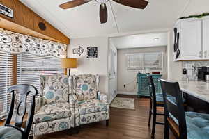 Living area with ceiling fan, dark wood finished floors, and baseboards