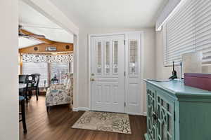 Entrance foyer featuring dark wood-type flooring, ceiling fan, lofted ceiling with beams, and baseboards