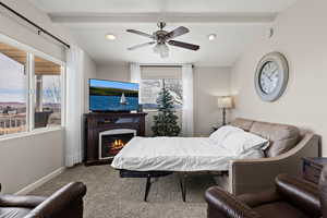 Carpeted bedroom featuring lofted ceiling with beams, a lit fireplace, recessed lighting, and baseboards