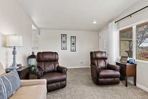 Carpeted living area with recessed lighting and baseboards