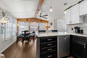 Kitchen with a peninsula, white cabinets, light countertops, stainless steel dishwasher, and pendant lighting