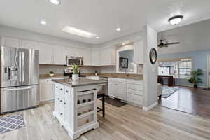 Kitchen featuring appliances with stainless steel finishes, white cabinets, a kitchen island, and open shelves