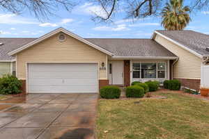 Single story home featuring a garage, brick siding, a front lawn, and a shingled roof