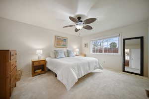 Bedroom featuring a ceiling fan, light carpet, and baseboards