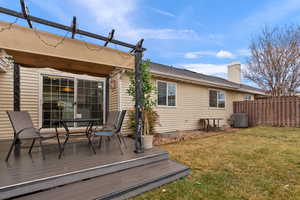 Deck with a yard, outdoor dining space, fence, and central AC unit