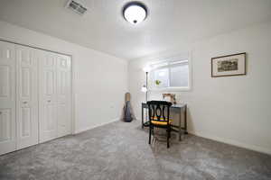 Home office with a textured ceiling, baseboards, visible vents, and light colored carpet