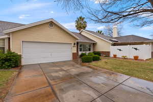 Ranch-style home featuring an attached garage, brick siding, fence, concrete driveway, and a front yard