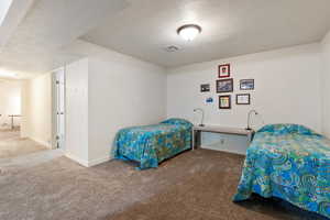 Bedroom with a textured ceiling, carpet flooring, visible vents, and baseboards