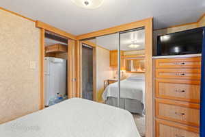 Carpeted bedroom with a textured wall, ornamental molding, a closet, and freestanding refrigerator