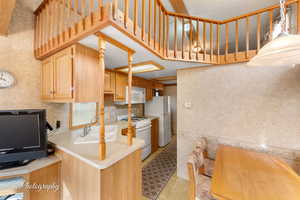 Kitchen with light countertops, decorative backsplash, a sink, white appliances, and a peninsula