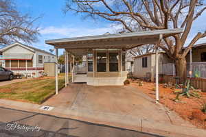 View of front facade featuring a carport and a front yard