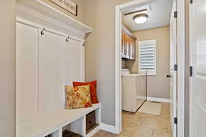 Mudroom featuring baseboards, washing machine and clothes dryer, and light tile patterned floors