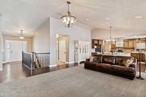 Living area with a chandelier, high vaulted ceiling, recessed lighting, baseboards, and dark wood-style floors