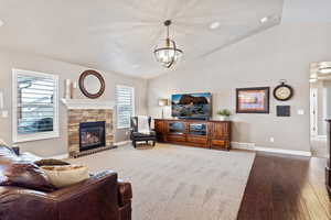 Living area with dark wood finished floors, a fireplace, vaulted ceiling, and baseboards