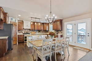 Dining area with vaulted ceiling, recessed lighting, dark wood-style flooring, and a notable chandelier