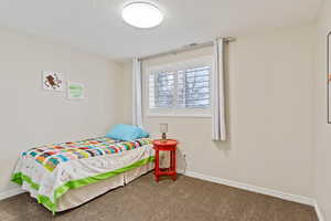 Carpeted bedroom with a textured ceiling and baseboards