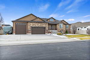 View of front of house featuring stucco siding, fence, a garage, stone siding, and driveway