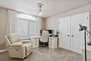 Office space with a textured ceiling, baseboards, and light colored carpet