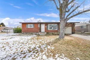 Ranch-style house featuring brick siding, deep and wide driveway, and an attached garage. There is possibly room for a trailer as well.