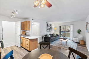 Kitchen featuring light countertops, visible vents, open floor plan, a sink, and light wood-type flooring