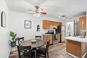 Kitchen featuring stainless steel appliances, stacked washer / dryer, light countertops, and under cabinet range hood