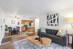 Living room with baseboards, visible vents, ceiling fan, wood finished floors, and track lighting