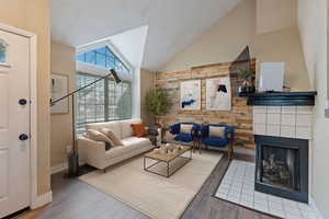 Living room featuring high vaulted ceiling, wood walls, a multi sided fireplace, and wood finished floors