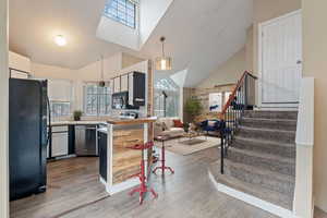 Kitchen featuring pendant lighting, light countertops, open floor plan, a peninsula, and black appliances