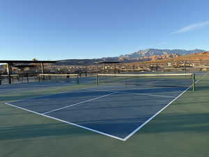 View of tennis court featuring a mountain view and fence