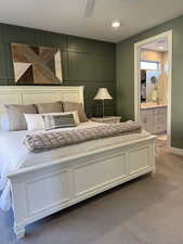 Bedroom featuring carpet, a decorative wall, a ceiling fan, and ensuite bathroom