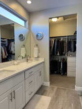 Full bathroom with double vanity, wood finished floors, a sink, and baseboards